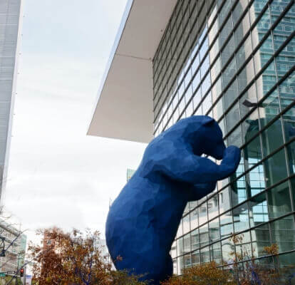 a large blue bear statue in front of a building.