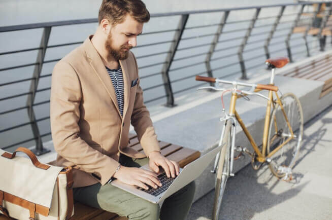 a man sitting on a bench using a laptop.
