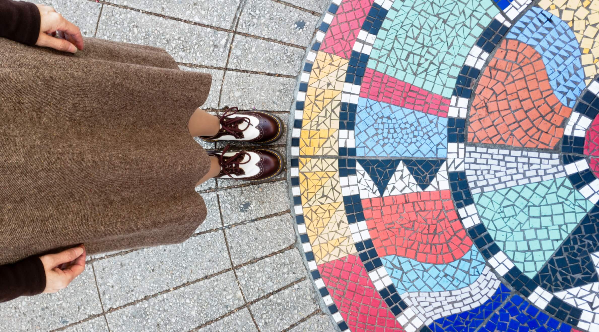 a person standing in front of a colorful mosaic floor.